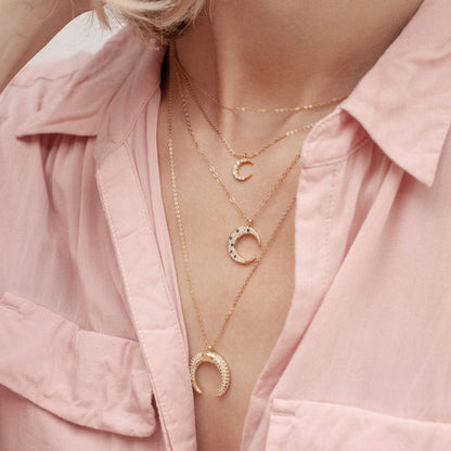 Woman wearing Maja Mini Moon 14k gold filled necklace layered with delicate gold chains in light pink button-up shirt