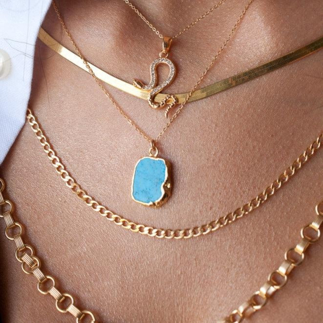 Woman wearing Mohave Turquoise 14k gold filled pendant necklace layered with gold herringbone chain and thick link chain