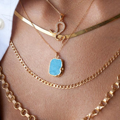Woman wearing Mohave Turquoise 14k gold filled pendant necklace layered with gold herringbone chain and thick link chain