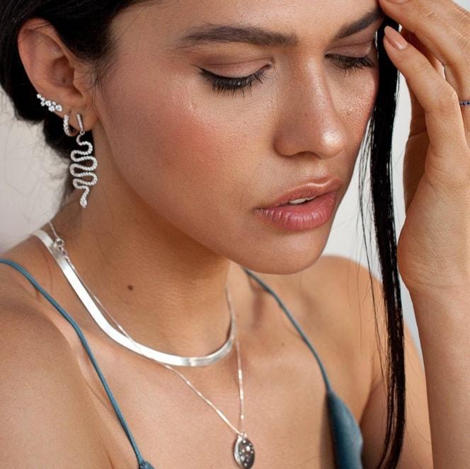 Woman wearing Naya Herringbone Chain sterling silver necklace layered with silver pendant