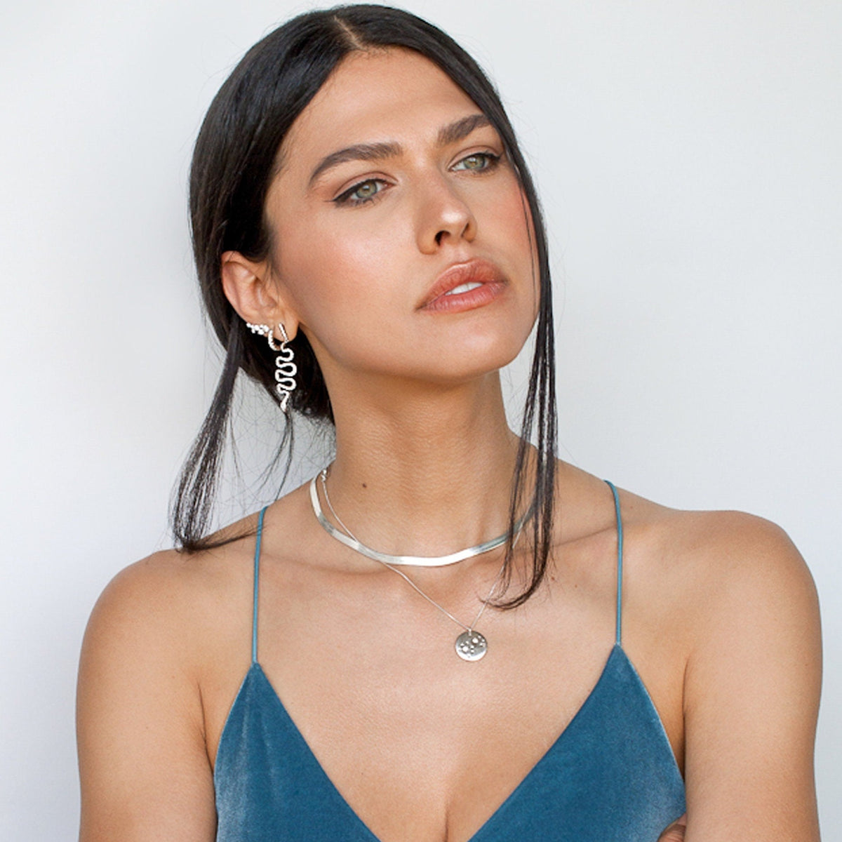 Woman wearing a teal top displaying Sterling Silver Vivia Snake Earrings and a silver choker necklace.