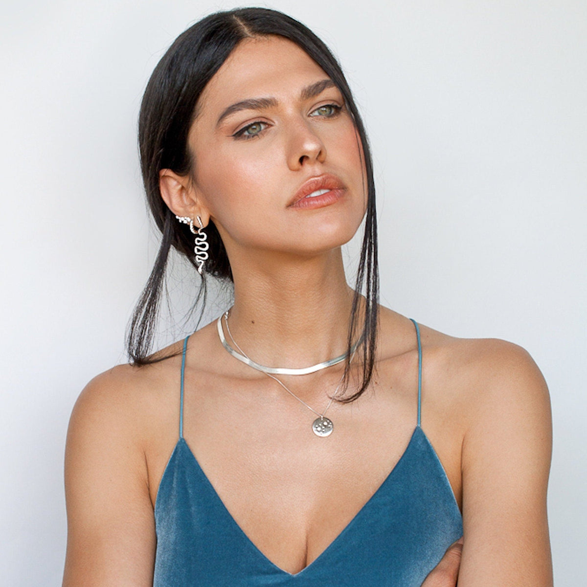Woman with dark hair wearing a blue dress styled with Sterling Silver Freja Ear Climbers and matching silver necklace.