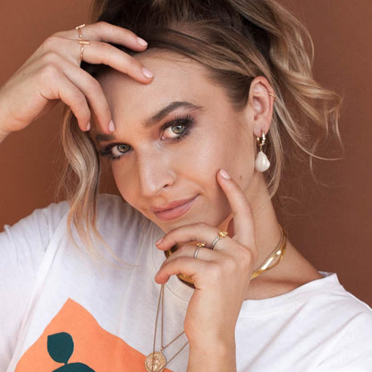 Woman with hand in hair wearing 14k gold filled Amia baroque pearl drop earrings