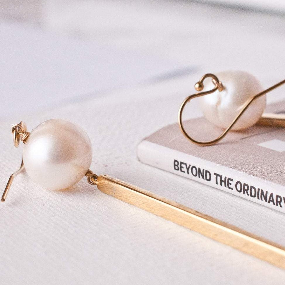 Gold bar pearl drop earrings displaying French hook ear wire clasps on white background.