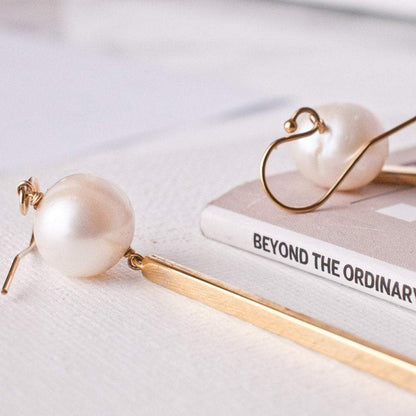Gold bar pearl drop earrings displaying French hook ear wire clasps on white background.