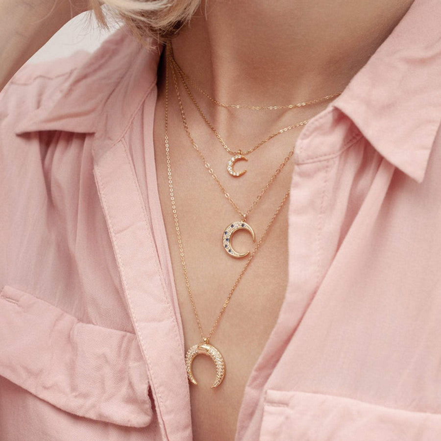 Small crescent moon necklace layered with medium moon necklace and double horn gold necklace.